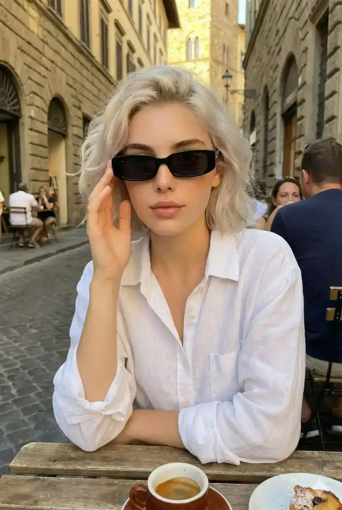 portrait of a stylish young woman sitting at an outdoor European café during golden hour