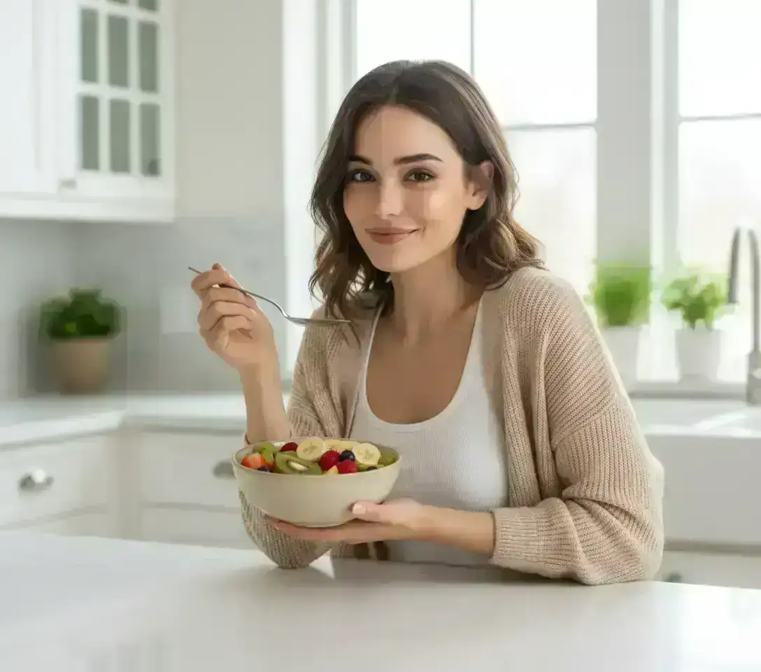 Woman sitting at kitchen counter holding a bowl of fruit